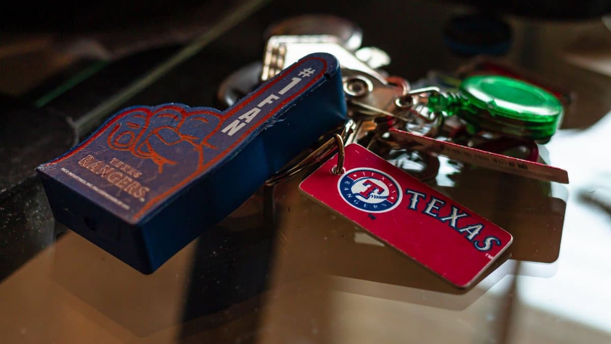 Detailed shot of Texas Rangers memorabilia keychains on a glass surface, capturing sports enthusiasm.