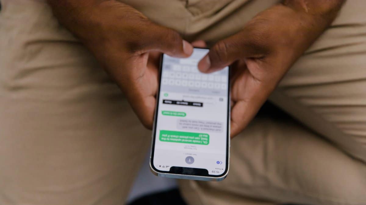 Close-up view of hands texting on a smartphone, focusing on the screen displaying messages.