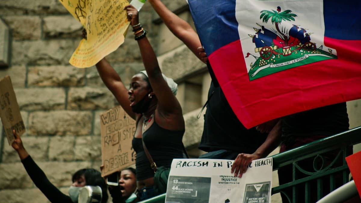 Protesters in Montreal holding Haitian flag and signs advocating for racial justice.