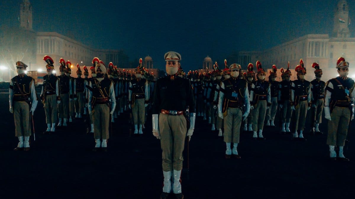 A group of soldiers in uniform stand in formation during a nighttime parade.