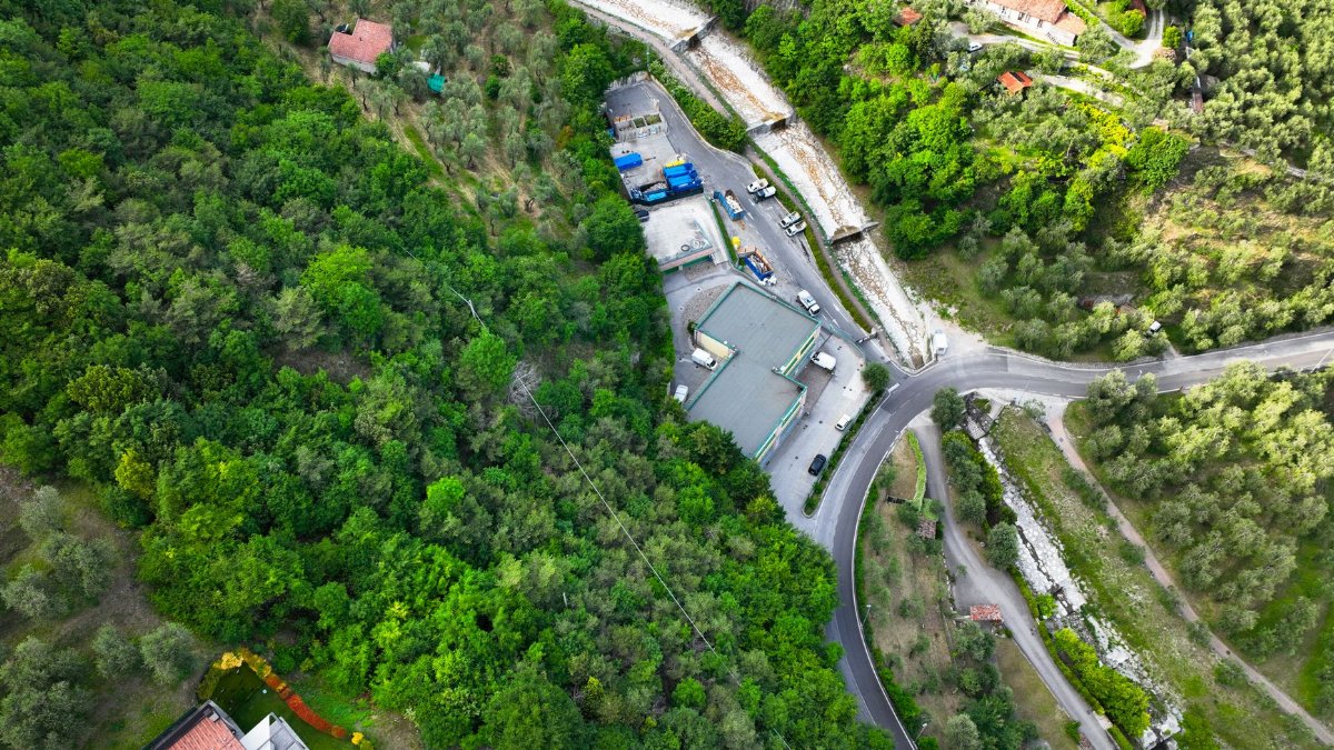 Scenic aerial view over lush green hills with roads and buildings, revealing a serene landscape.