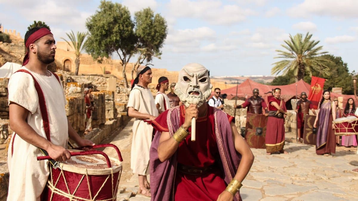 Actors in Roman attire perform at historic ruins in Morocco, blending culture and history.