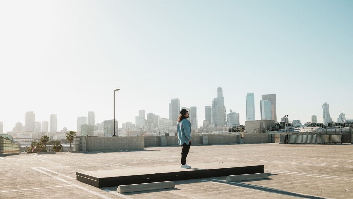 A lone individual on a rooftop with a stunning view of the Los Angeles skyline under clear skies.