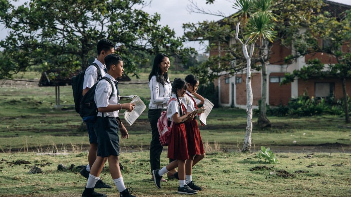 Group of students and a teacher walking outdoors in school uniforms.