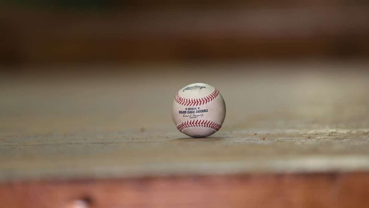 Close-up of a baseball on a wooden floor, highlighting sports equipment and leisure.