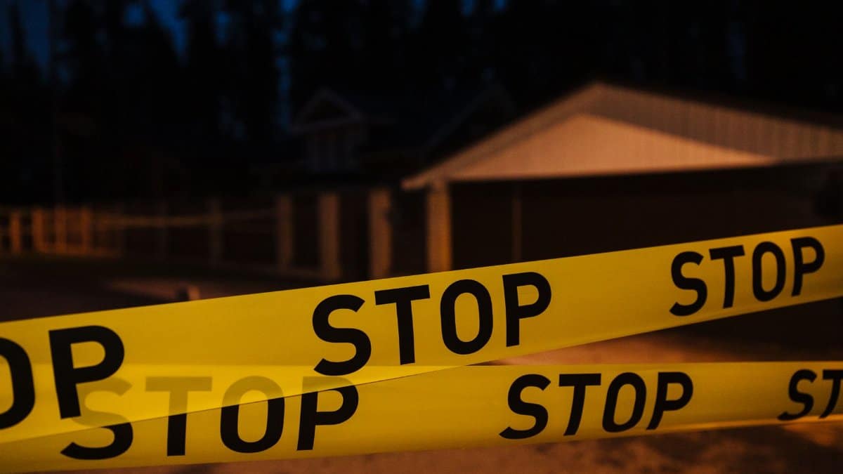 Yellow stop tape blocking a residential street at night, creating a restricted area.