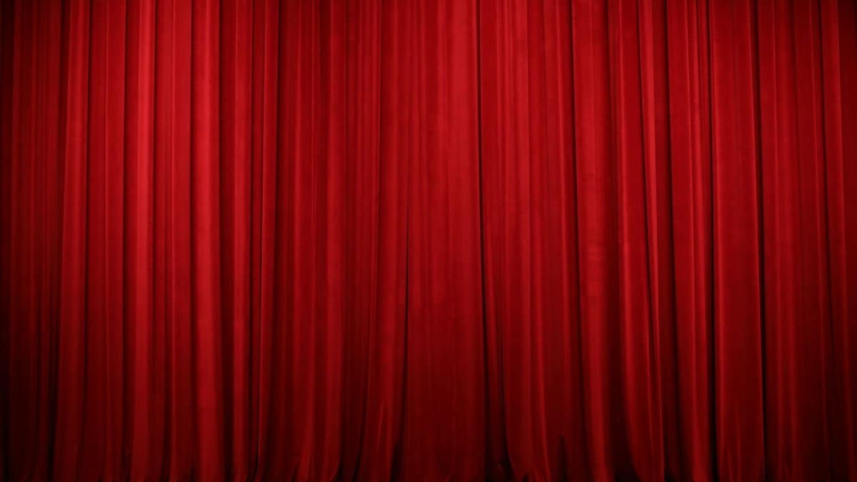 Elegant red theater curtains creating a dramatic stage backdrop indoors.