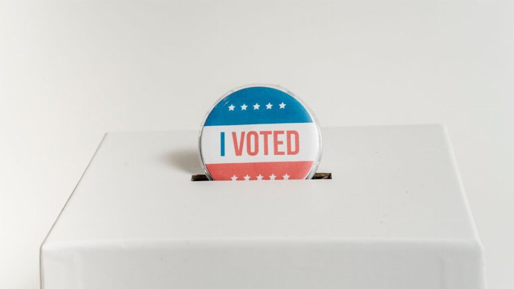 Close-up of an I Voted badge on a ballot box, symbolizing voting in the USA elections.
