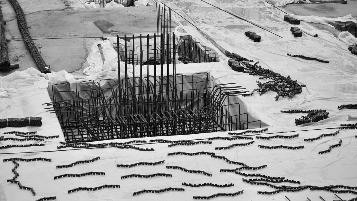 Black and white aerial shot of a construction site with rebar framework, showcasing industrial building materials and layout.