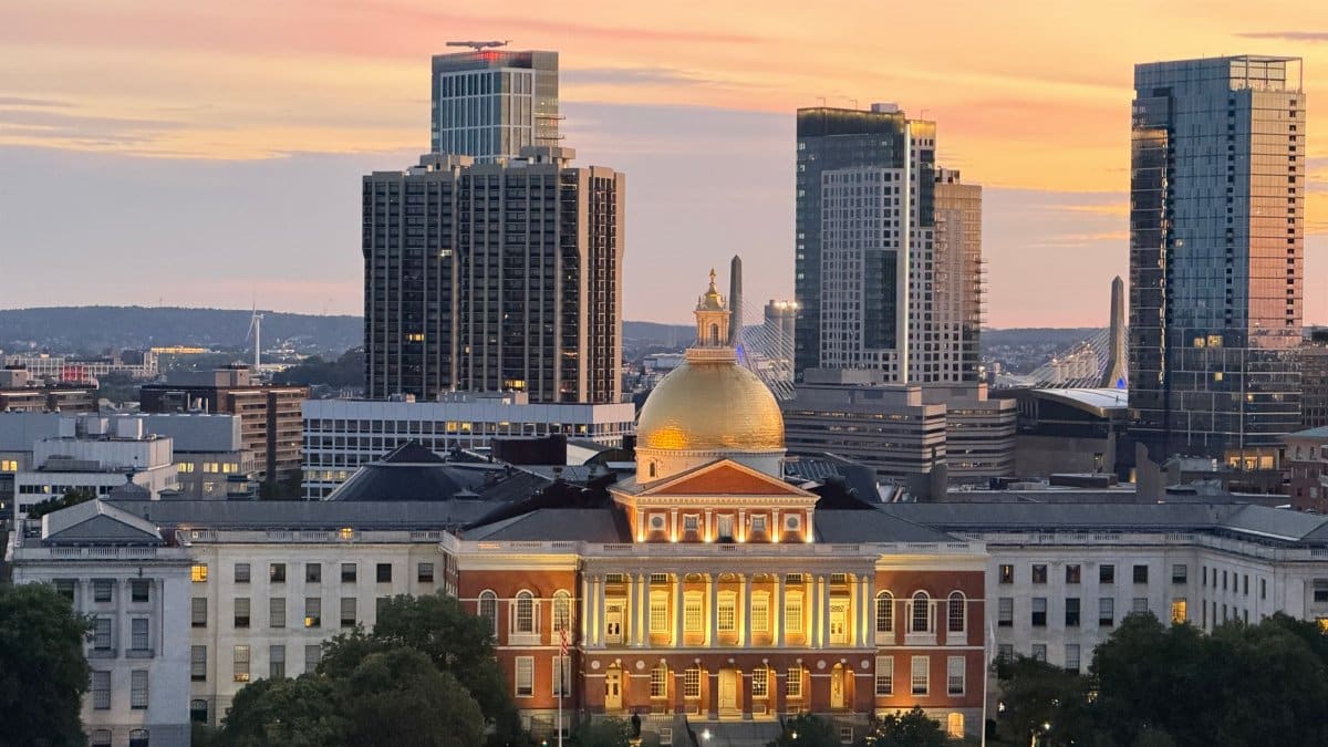 A breathtaking view of Boston's skyline with the Massachusetts State House at sunset, showcasing its iconic golden dome.