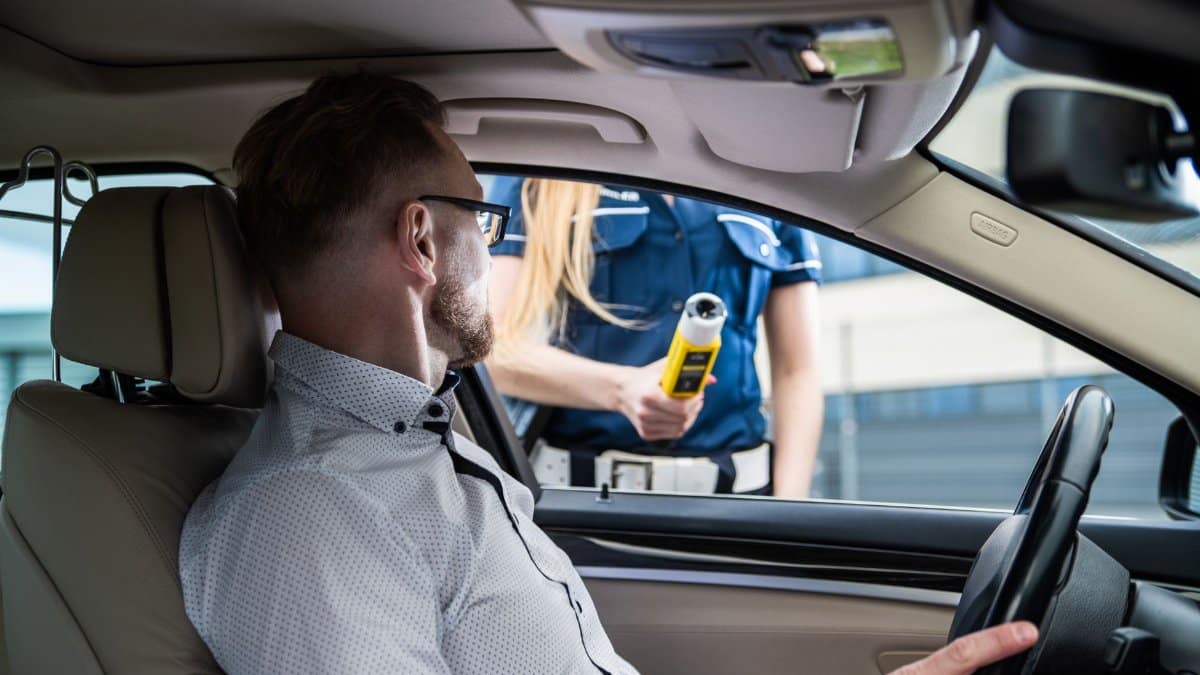 Officer administering a breathalyzer test to a driver during a roadside check for safety.