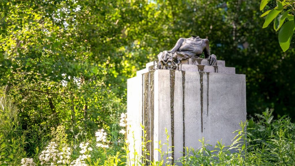 A tranquil statue surrounded by lush greenery in a New York garden setting.