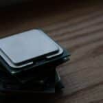 Close-up of multiple computer CPUs stacked on a wooden surface, showcasing technology components.