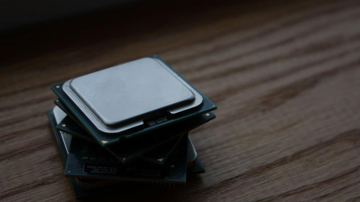 Close-up of multiple computer CPUs stacked on a wooden surface, showcasing technology components.