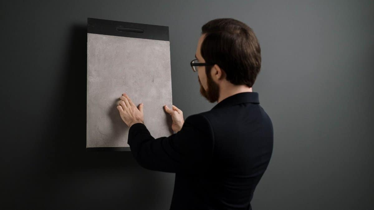 Professional interior designer examining a gray tile sample indoors, focused on material texture and design.