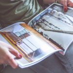 A person relaxes on a sofa, flipping through an architecture-themed magazine.
