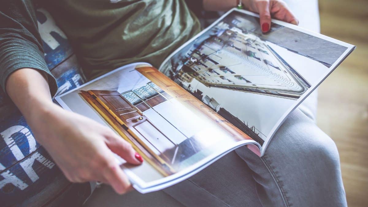A person relaxes on a sofa, flipping through an architecture-themed magazine.