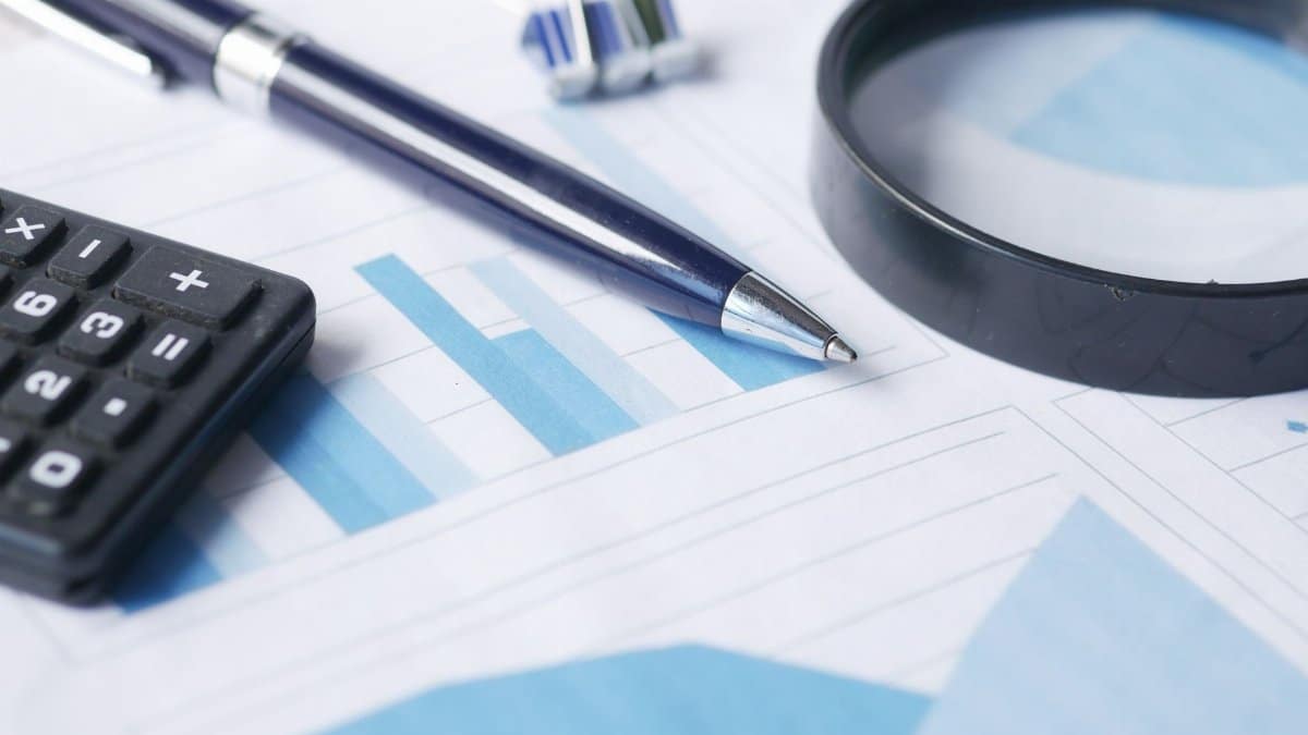 Close-up of calculator, pen, and magnifying glass on financial documents.