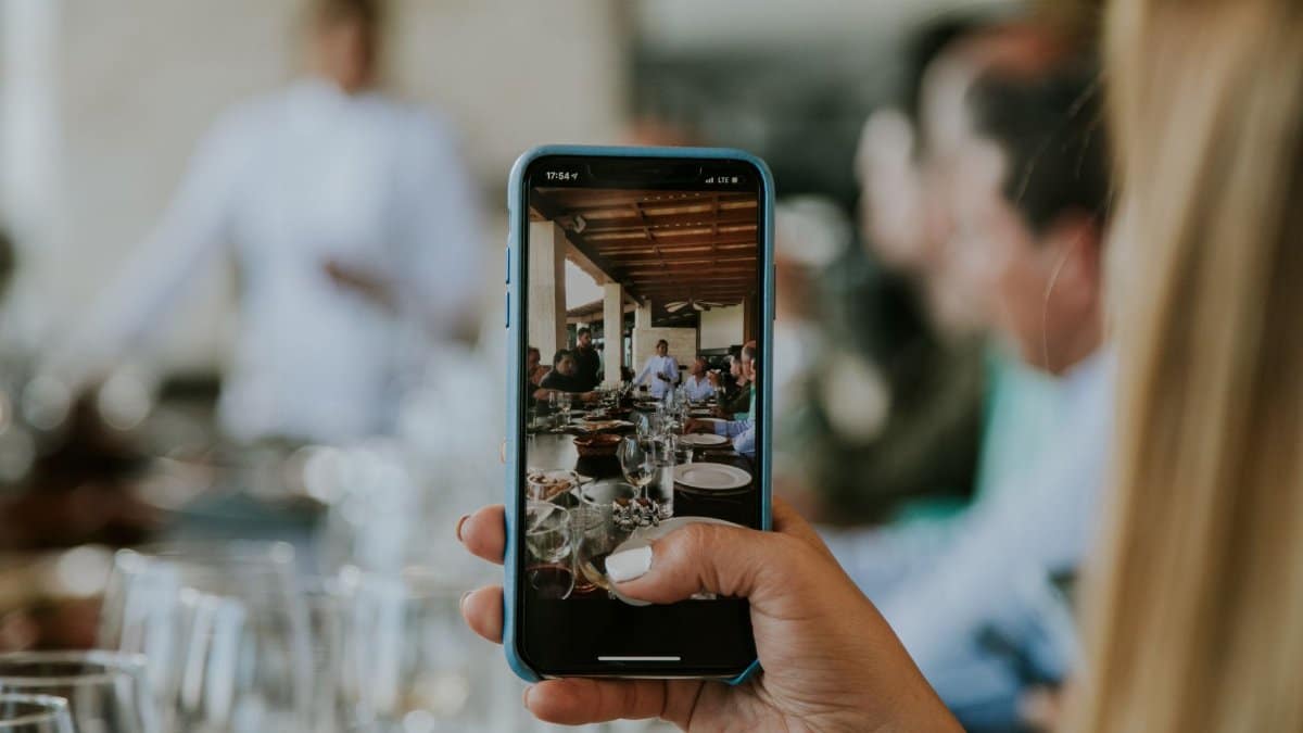 Close-up of a smartphone capturing a lively dining scene indoors.