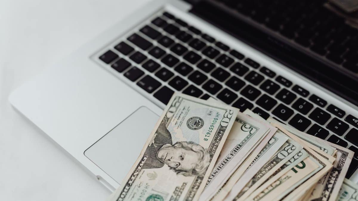 Close-up of US dollar banknotes on a laptop keyboard symbolizing online finance and technology.