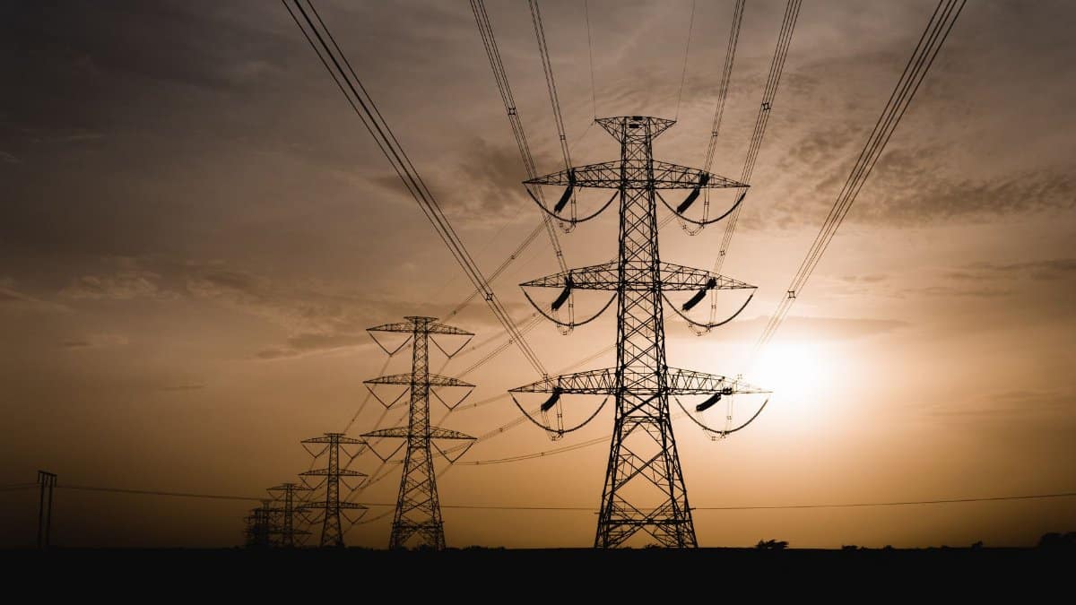 Silhouetted power lines stretch across the landscape at sunset, capturing electric tranquility.