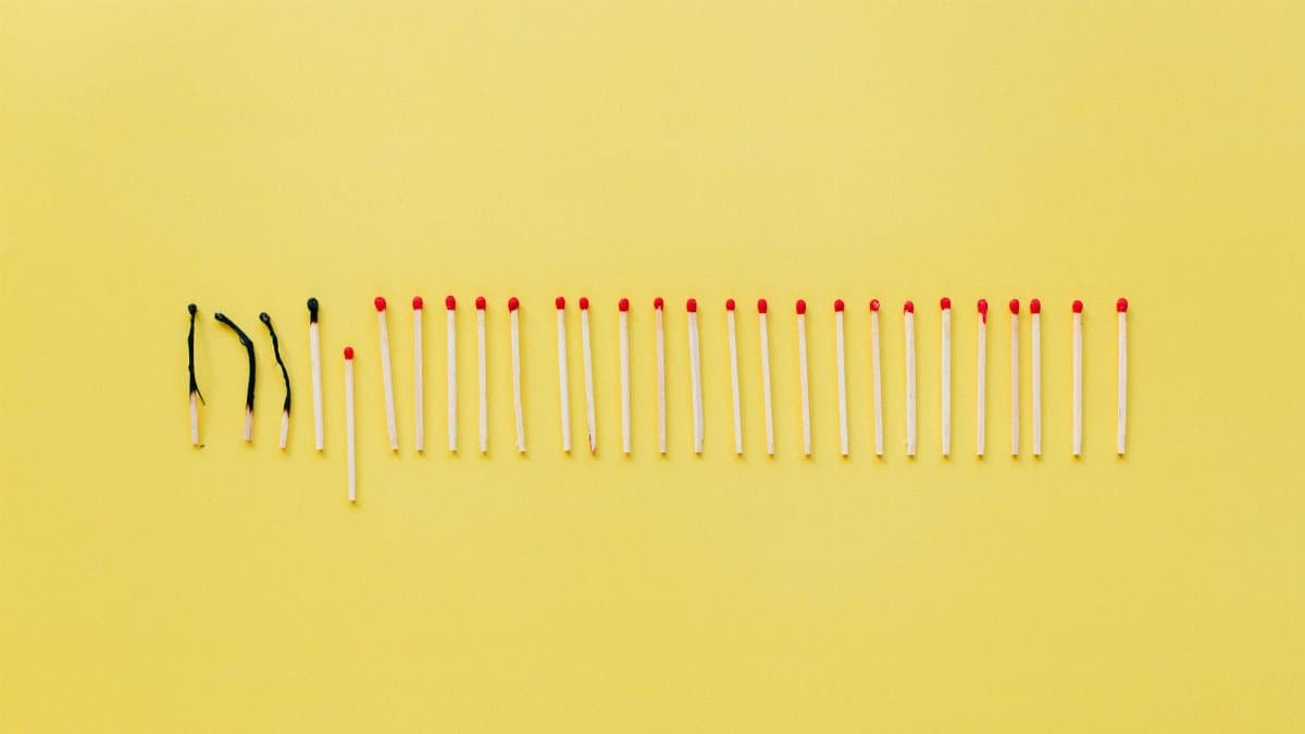 A conceptual still life photo of burnt and unlit matches on a vibrant yellow background.