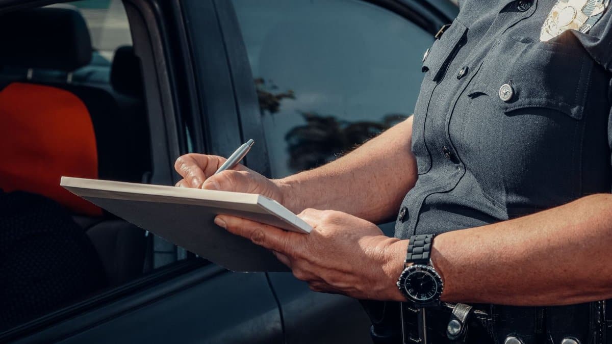 Close-up of a police officer writing a ticket by a car window. Law enforcement scene.