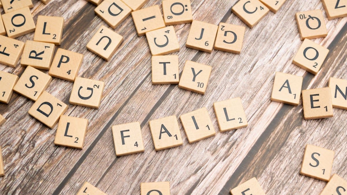 Scrabble tiles on wood form 'FAIL', symbolizing defeat and reflection.