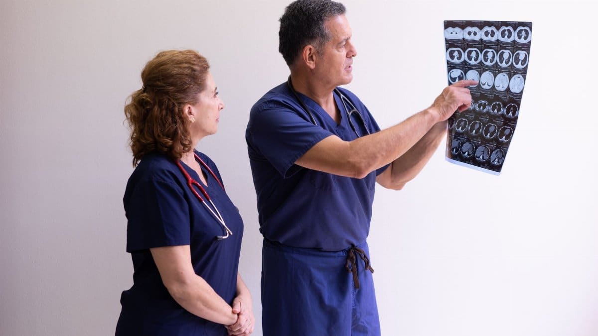 Two healthcare professionals in scrubs examining a medical x-ray image, discussing diagnosis.
