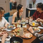 A diverse group of friends sharing dinner at a cozy dining table with wine and lighted candles.