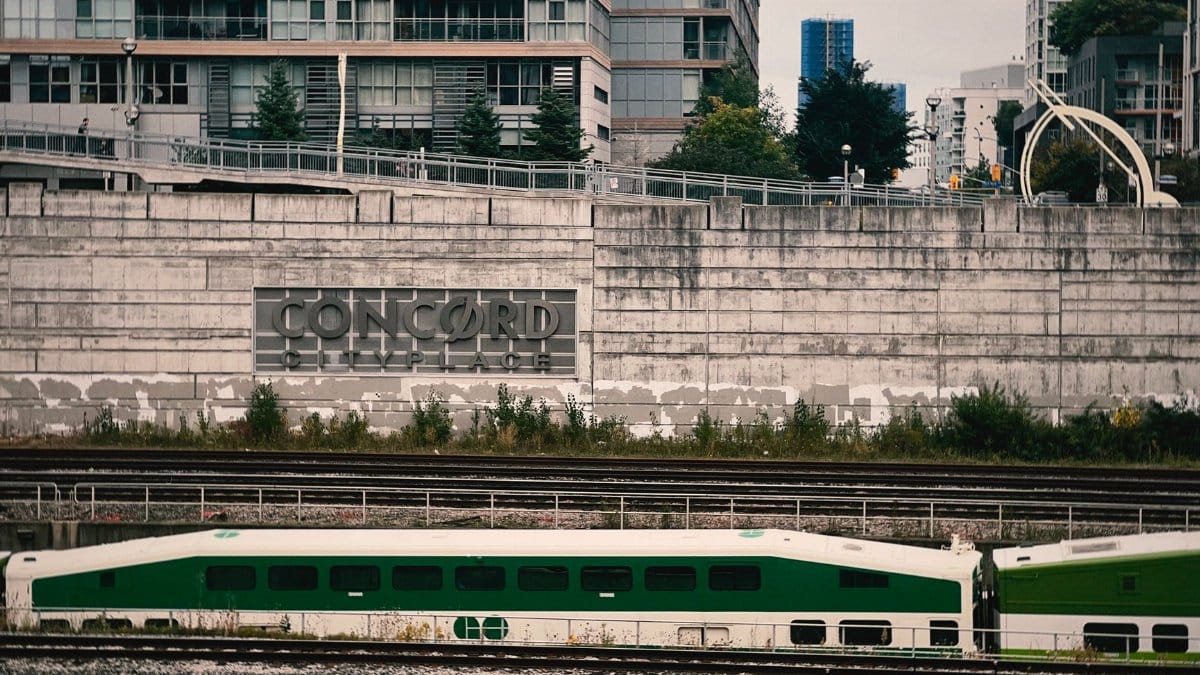 Green train in urban area near Concord Cityplace buildings, showcasing modern architecture and transport.