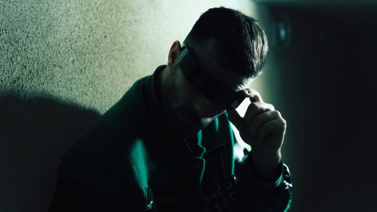 Shadowy portrait of a man wearing sunglasses and a green jacket, exuding mystery and style.