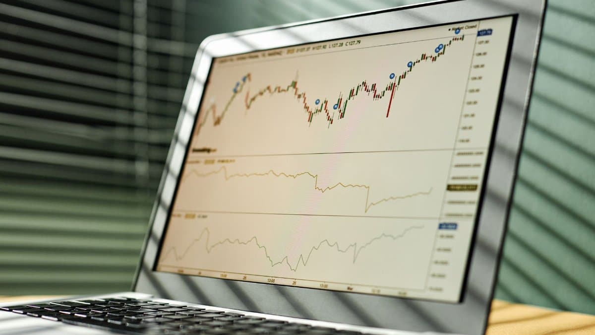 Close-up of a laptop displaying stock market data and graphs in an office setting.