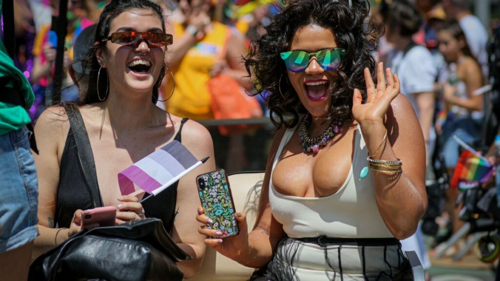 Two women joyfully participating in the colorful New York Pride Parade.