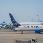 A view of diverse airplanes alongside a busy airport terminal and runway.