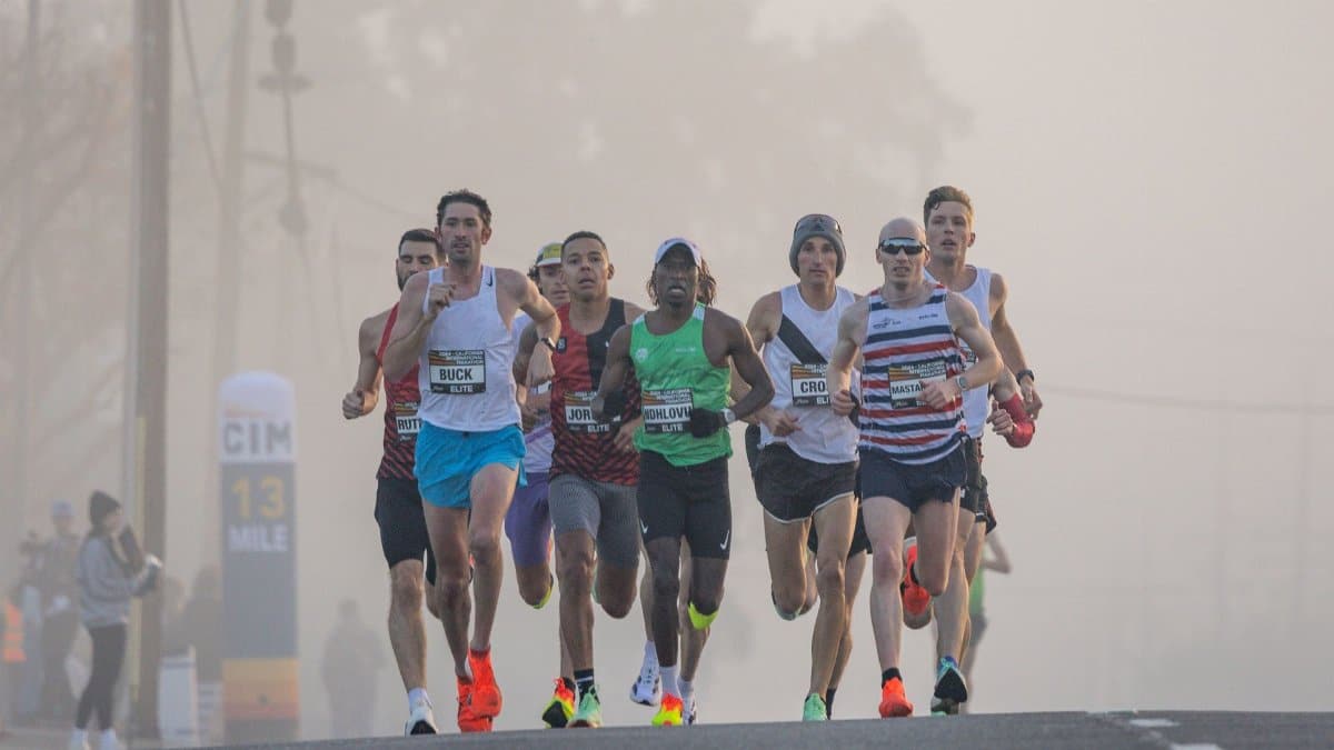 Dynamic shot of marathon runners competing in a misty urban setting, emphasizing endurance and athleticism.
