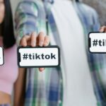 Young adults holding smartphones with TikTok hashtag, showcasing social media engagement.