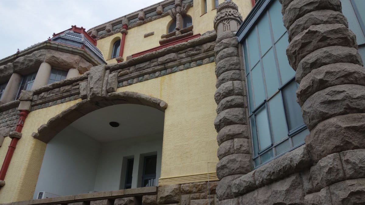Detailed view of an historic building with stone and yellow facade showcasing unique architectural style.