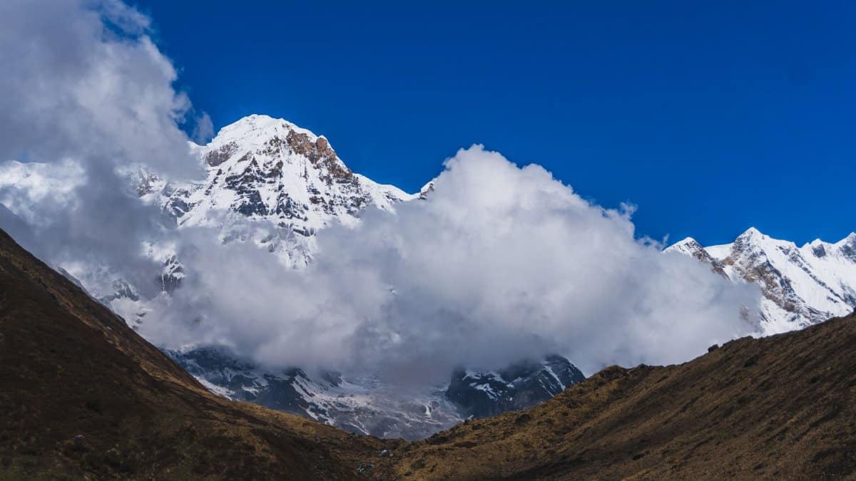 Spectacular view of snow-capped Machhapuchchhre peak surrounded by clouds in Nepal.