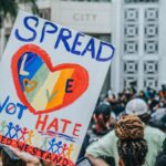 A colorful protest sign promoting love over hate during a rally at City Hall, capturing a peaceful advocacy movement.