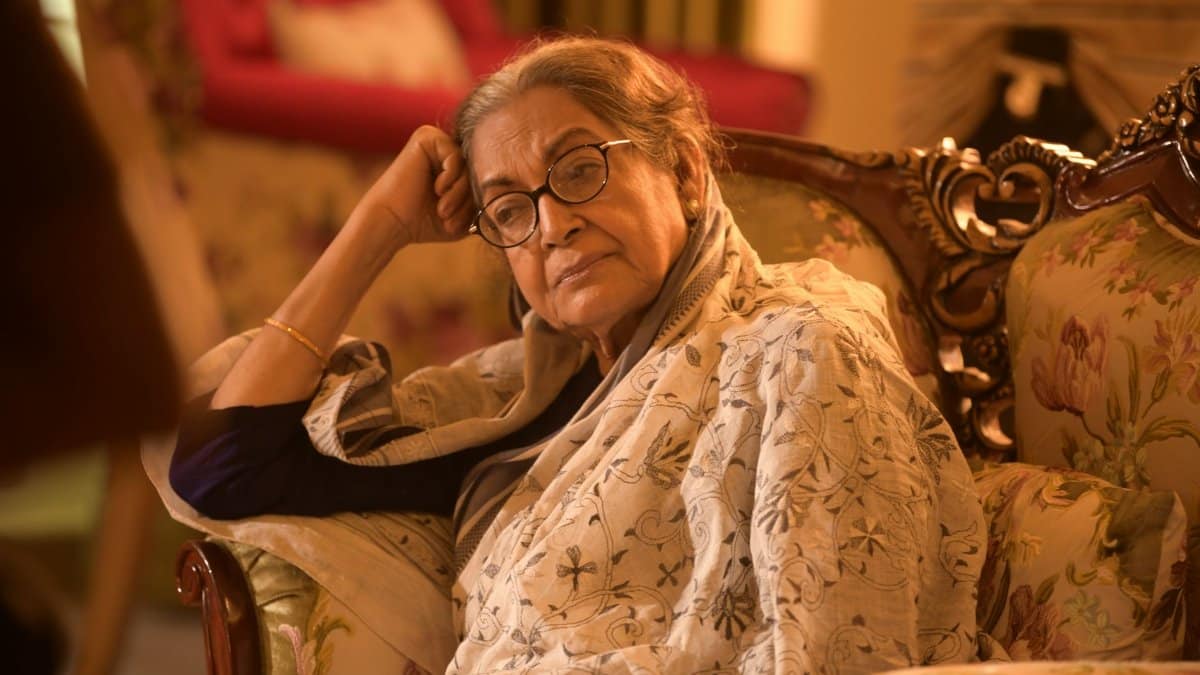 Relaxed elderly woman sitting on a vintage sofa indoors. A warm, cozy ambiance fills the room.