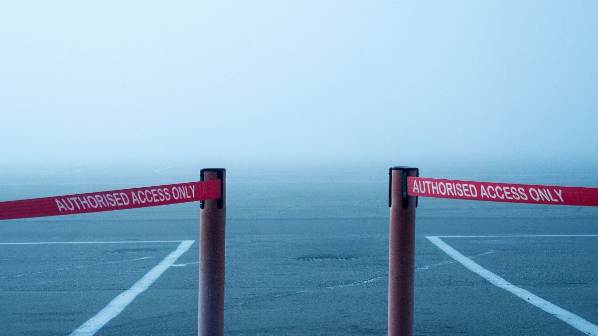 Misty airport runway blocked by safety barriers for authorized access only.