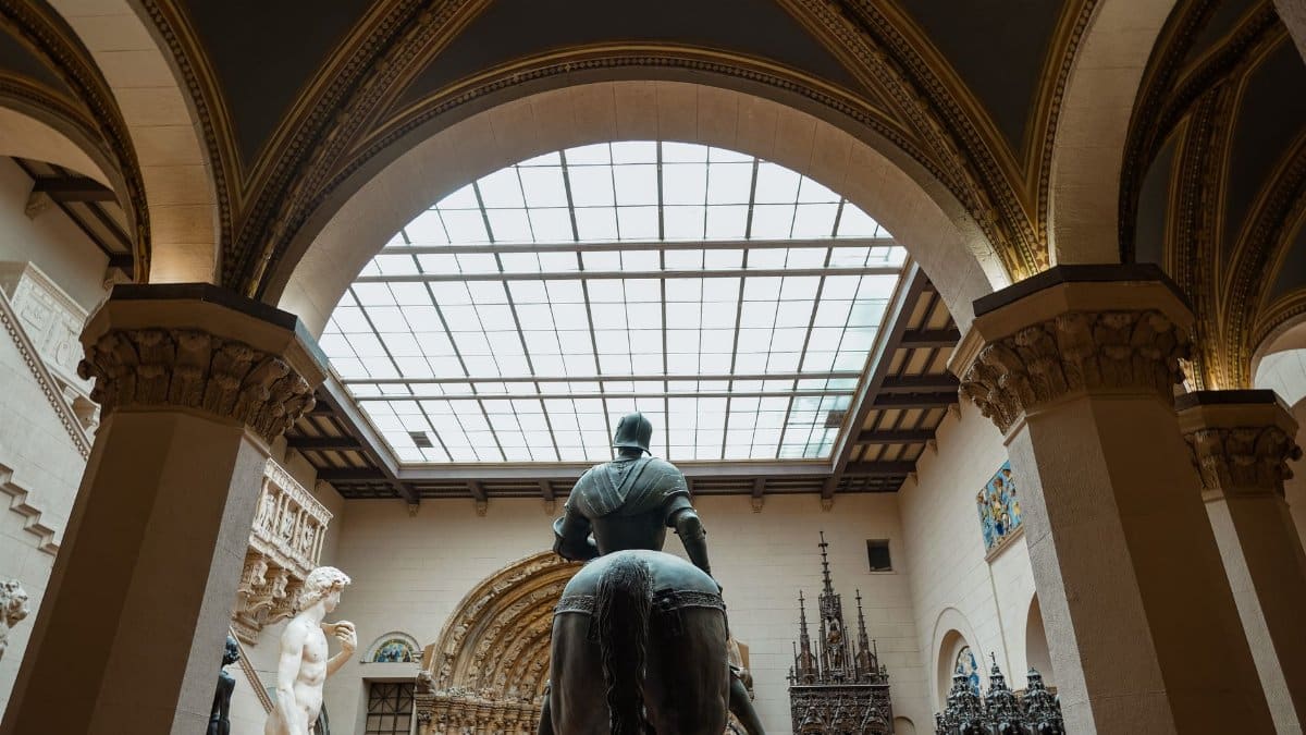 Back view of sculptures in a museum with intricate architectural details and arched ceilings.