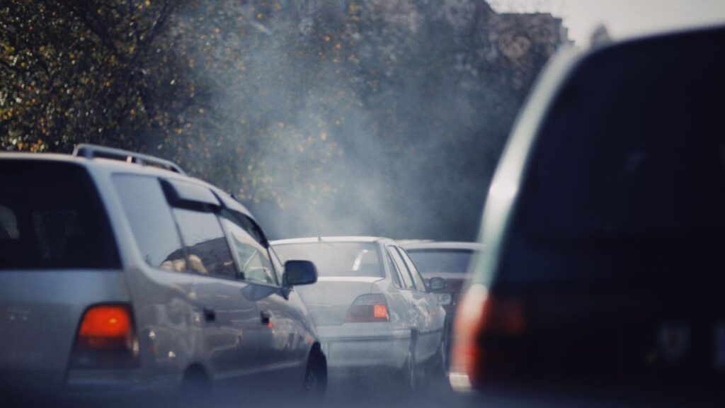 City traffic jam with cars emitting smoke on a busy road.