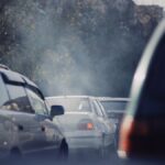 City traffic jam with cars emitting smoke on a busy road.