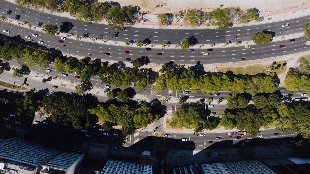 Drone view of Rio de Janeiro streets, showcasing vibrant urban greenery and bustling traffic.