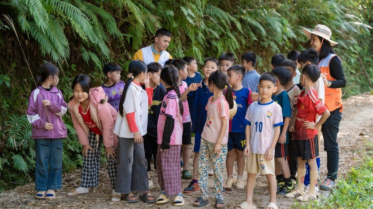 Group of children engaged in outdoor learning activity on a nature trail with two adult guides.