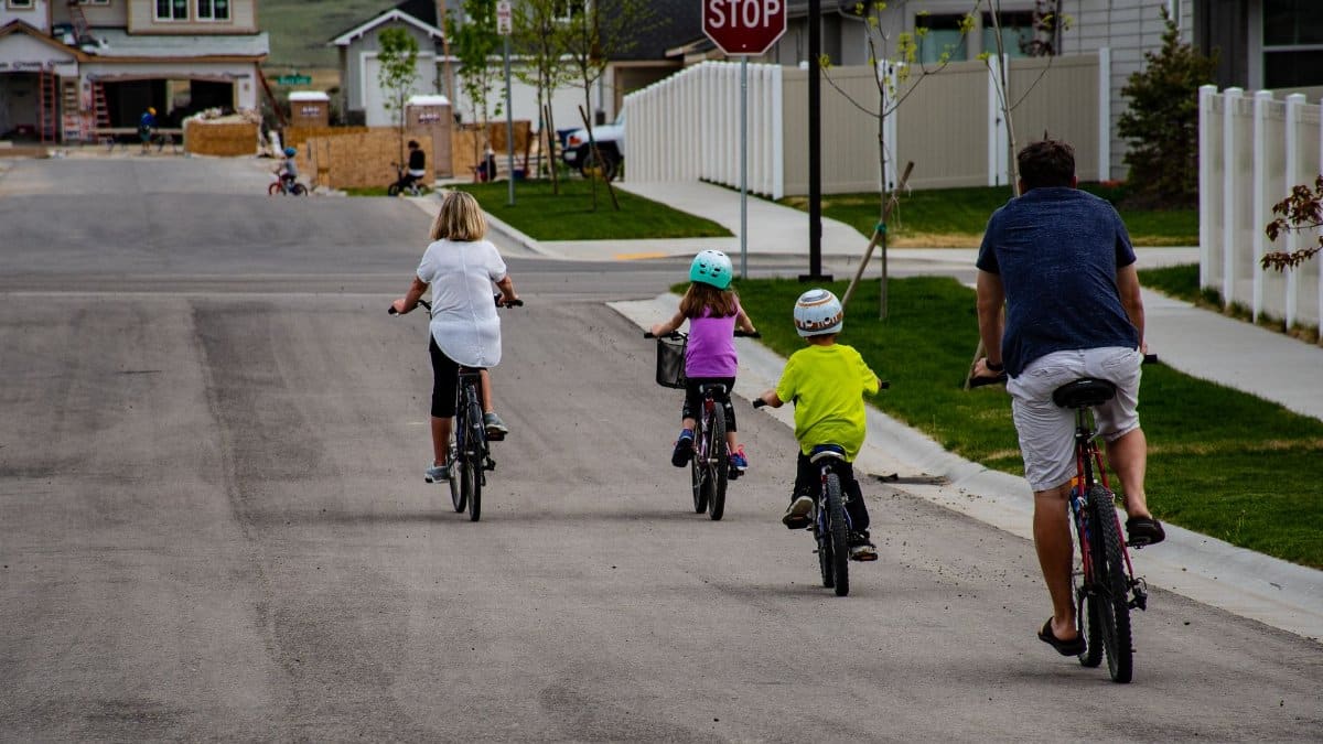 A family enjoys biking together on a suburban street, highlighting active outdoor lifestyle.