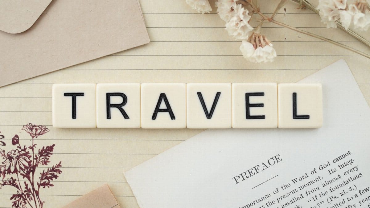 Travel-themed flat lay with Scrabble tiles, dried flowers, and stationery creating a vintage vibe.