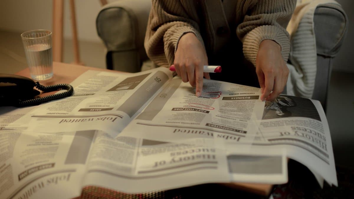 Close-up of a woman reading job listings in a newspaper, highlighting employment search.